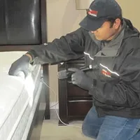 Bed bug inspection technician checking a mattress and bed frame for signs of infestation in Bradenton, FL